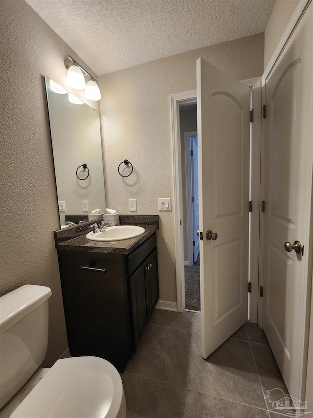 bathroom with tile patterned floors, vanity, a textured ceiling, and toilet