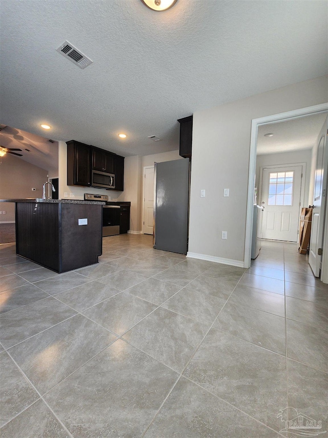 kitchen with a center island, sink, ceiling fan, a textured ceiling, and stainless steel appliances