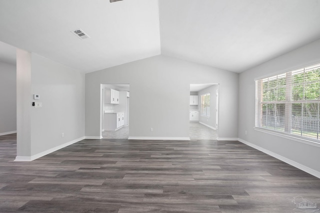 unfurnished living room with vaulted ceiling, dark wood-style flooring, visible vents, and baseboards