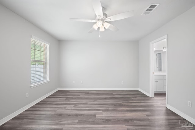 empty room with a ceiling fan, visible vents, dark wood finished floors, and baseboards