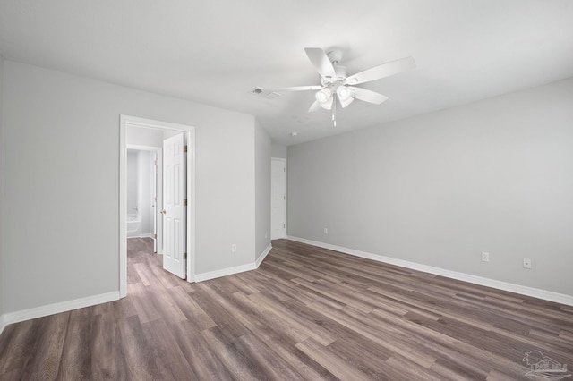 empty room featuring dark wood-style floors, a ceiling fan, visible vents, and baseboards