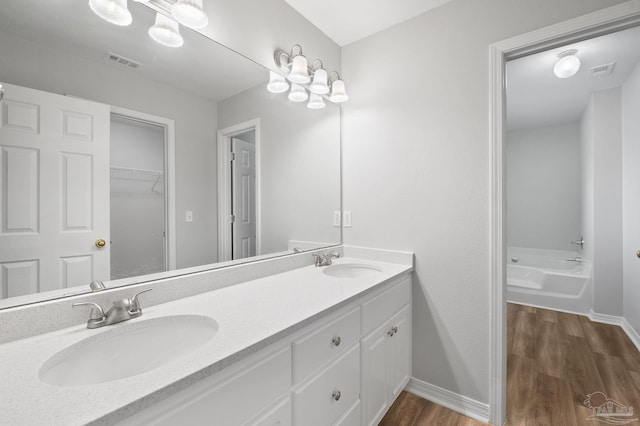 full bath featuring wood finished floors, a sink, and visible vents