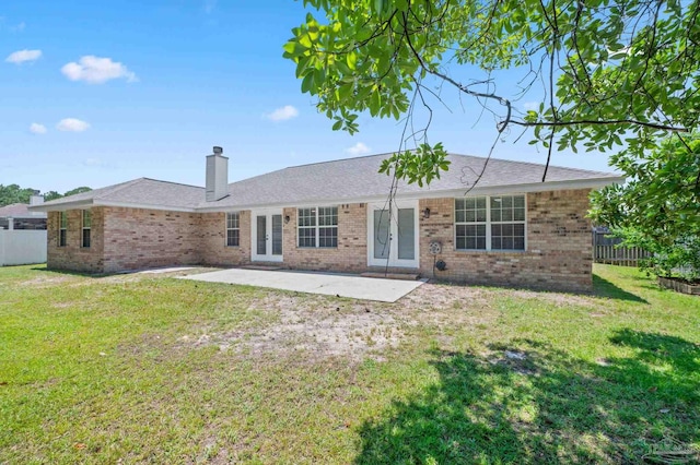 rear view of house featuring french doors, brick siding, a patio, and a lawn