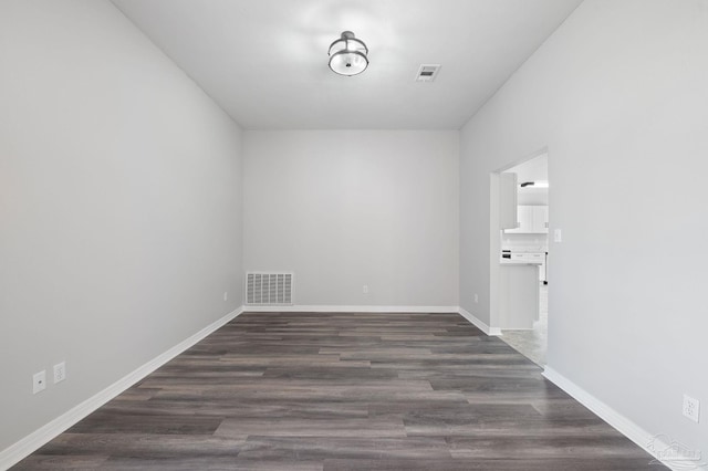 unfurnished room featuring baseboards, visible vents, and dark wood-style flooring