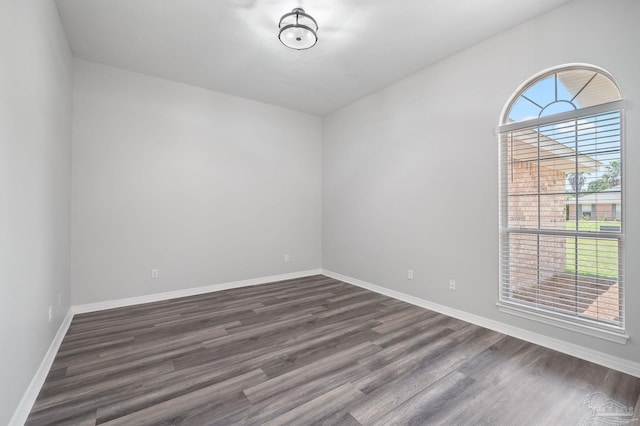 unfurnished room with dark wood finished floors and baseboards