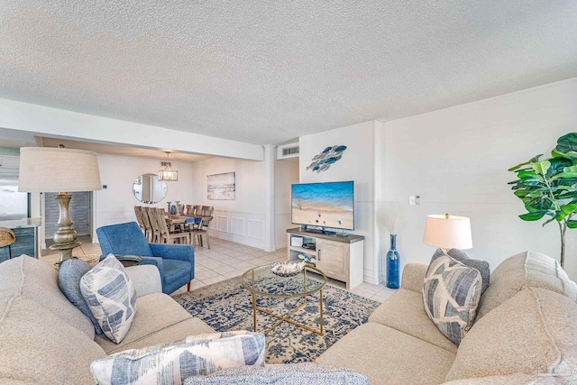 living room with a textured ceiling, light tile patterned floors, and a healthy amount of sunlight