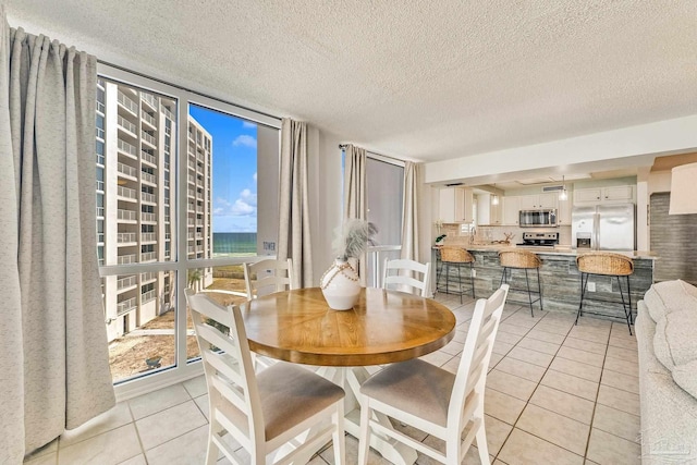 dining area featuring expansive windows, light tile patterned floors, and a textured ceiling