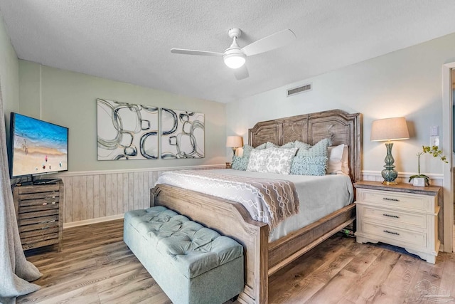 bedroom featuring ceiling fan, hardwood / wood-style flooring, and a textured ceiling