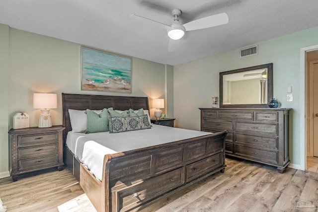 bedroom with light hardwood / wood-style flooring, a textured ceiling, and ceiling fan