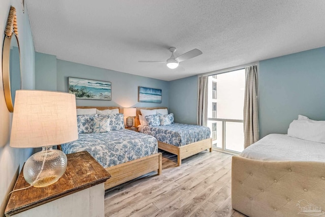 bedroom featuring a textured ceiling, light wood-type flooring, and ceiling fan