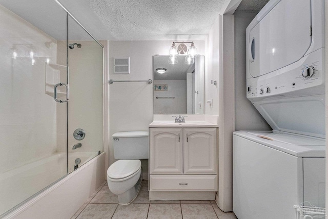 full bathroom with toilet, stacked washer and dryer, shower / bath combination with glass door, vanity, and a textured ceiling