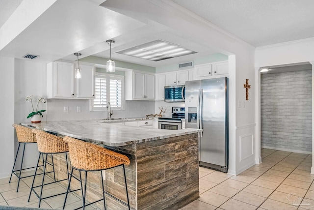 kitchen with light tile patterned flooring, kitchen peninsula, white cabinetry, stainless steel appliances, and a breakfast bar area