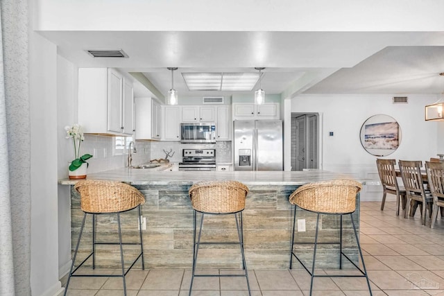 kitchen with a kitchen bar, white cabinets, appliances with stainless steel finishes, and kitchen peninsula