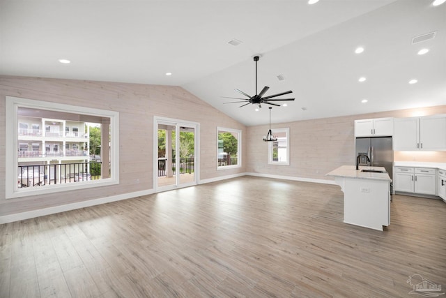 unfurnished living room with ceiling fan, hardwood / wood-style flooring, sink, and vaulted ceiling