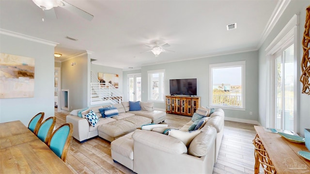 living room featuring ornamental molding, light wood-type flooring, ceiling fan, and a healthy amount of sunlight