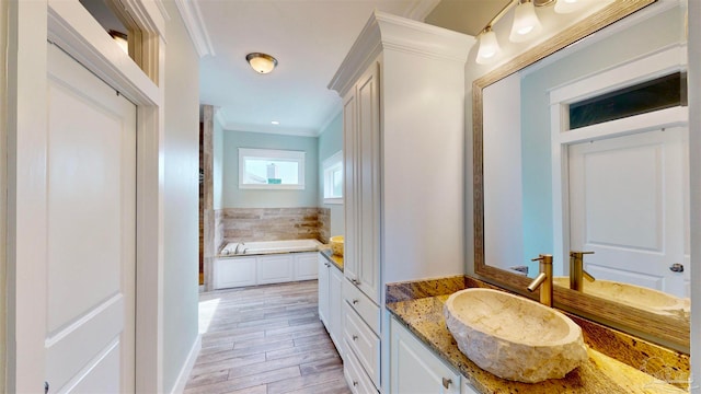 bathroom with a tub to relax in, vanity, hardwood / wood-style flooring, and ornamental molding