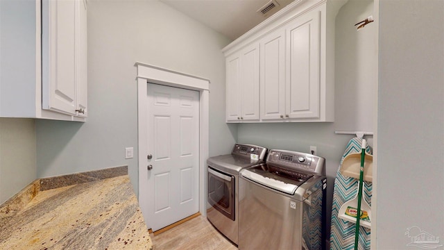 laundry area featuring washer and clothes dryer, cabinets, and light wood-type flooring