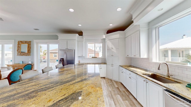 kitchen featuring white cabinetry, sink, stainless steel appliances, light stone counters, and ornamental molding