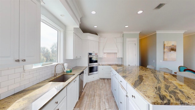 kitchen with white cabinetry, sink, tasteful backsplash, light stone counters, and light wood-type flooring