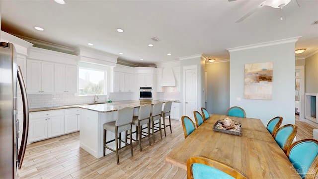 dining room featuring light wood-type flooring, ceiling fan, crown molding, and sink