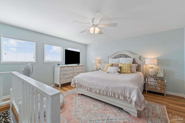 bedroom with a textured ceiling, wood finished floors, a ceiling fan, and baseboards