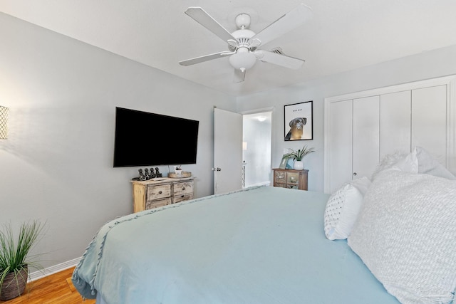 bedroom with a closet, ceiling fan, baseboards, and wood finished floors