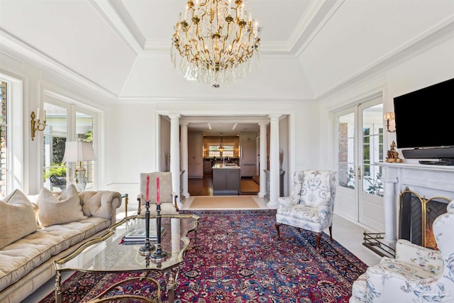 living room with an inviting chandelier, crown molding, plenty of natural light, and decorative columns