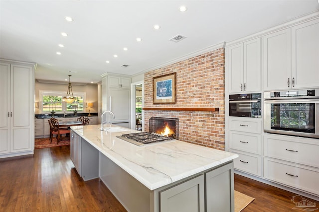 kitchen with stainless steel appliances, a large island, light stone countertops, and hanging light fixtures