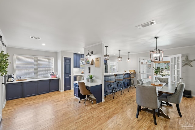 dining room featuring crown molding, visible vents, and light wood-type flooring