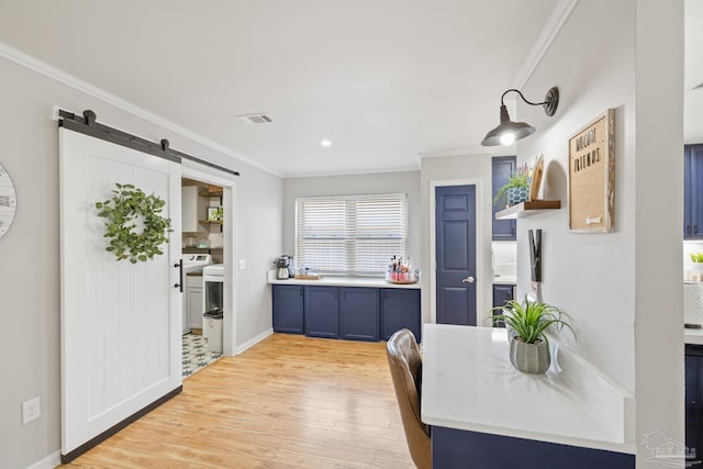 dining area with visible vents, light wood-type flooring, a barn door, and ornamental molding