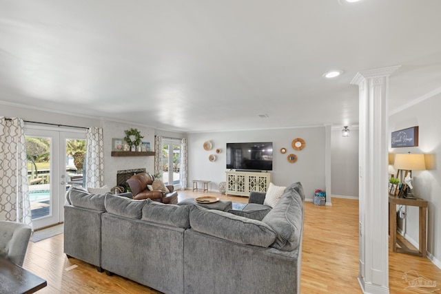 living room with baseboards, a fireplace, light wood-style flooring, and crown molding