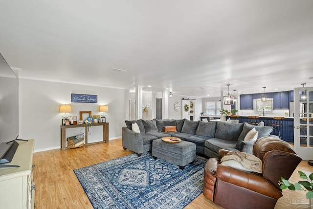 living area with visible vents, a notable chandelier, light wood-style floors, and baseboards