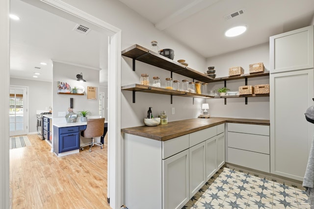 kitchen with open shelves, visible vents, stainless steel range with gas cooktop, and butcher block counters