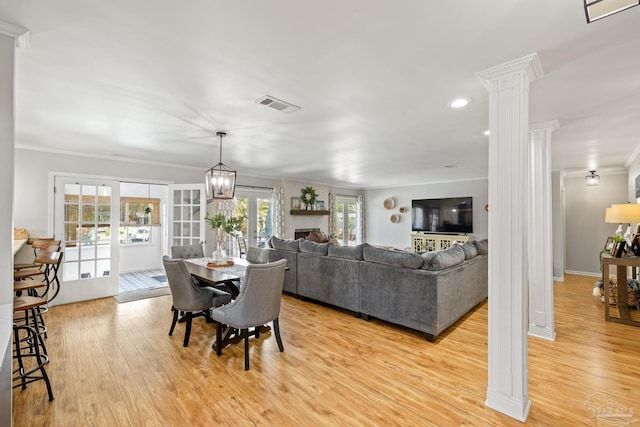 dining space featuring baseboards, visible vents, decorative columns, crown molding, and light wood-type flooring