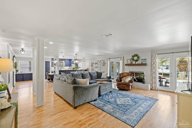 living room with french doors, light wood-style floors, visible vents, and decorative columns