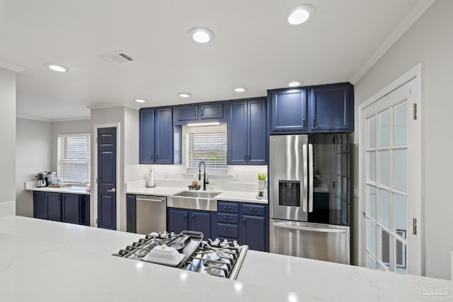 kitchen featuring visible vents, crown molding, appliances with stainless steel finishes, blue cabinets, and a sink