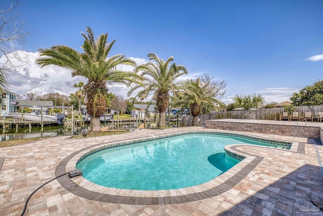 view of pool with a patio area, fence, a fenced in pool, and a boat dock