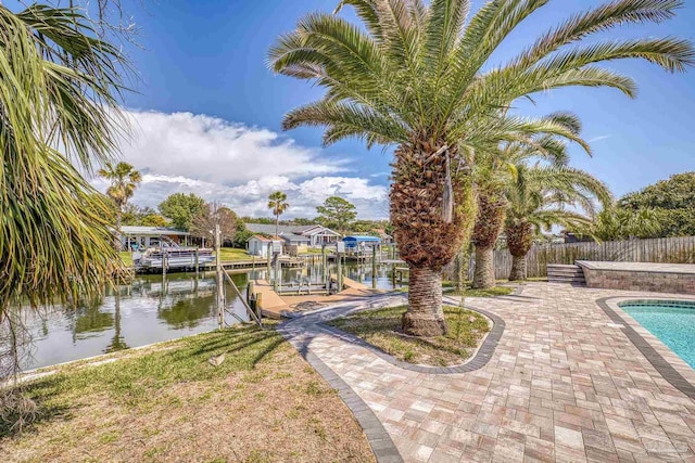 dock area featuring a fenced in pool, a water view, fence, boat lift, and a patio