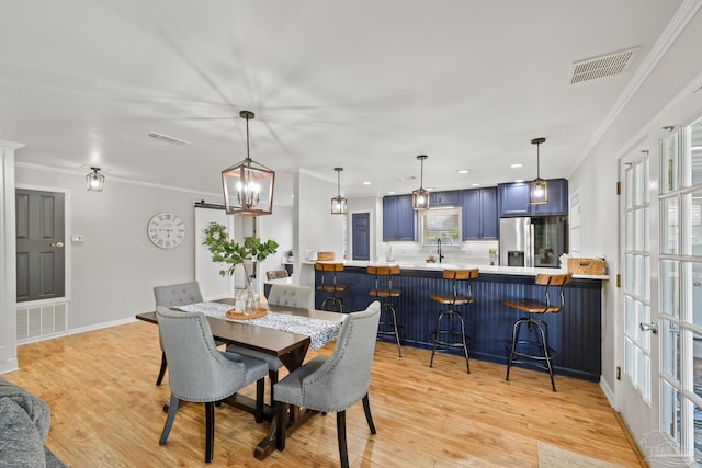 dining area featuring visible vents, crown molding, and light wood-style floors