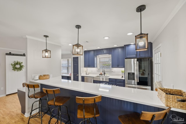 kitchen with blue cabinets, a kitchen breakfast bar, appliances with stainless steel finishes, and a peninsula