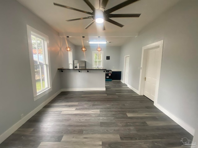 unfurnished room featuring ceiling fan, dark hardwood / wood-style floors, and a healthy amount of sunlight