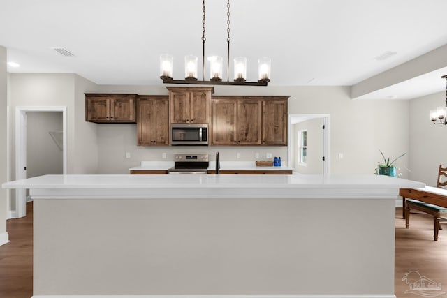 5681 Paddlewheel Dr, Milton, FL 32583 - kitchen featuring appliances with stainless steel finishes, a chandelier, light countertops, a large island with sink, and dark wood finished floors
