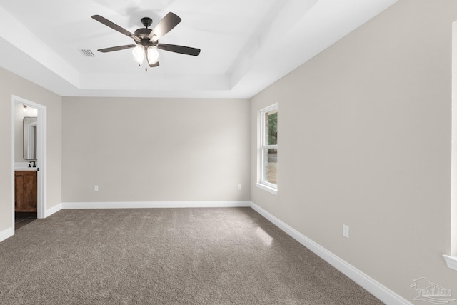 5681 Paddlewheel Dr, Milton, FL 32583 - unfurnished bedroom featuring a tray ceiling, dark carpet, baseboards, and ensuite bathroom