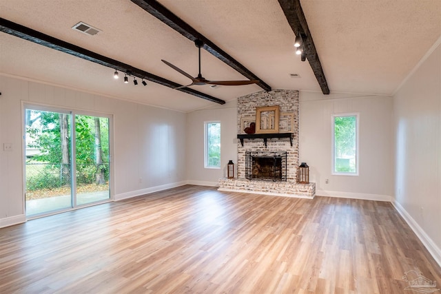 unfurnished living room featuring lofted ceiling with beams, light wood-type flooring, a textured ceiling, a brick fireplace, and ceiling fan