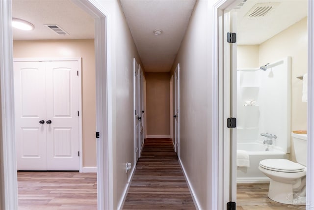 hallway with hardwood / wood-style flooring and a textured ceiling