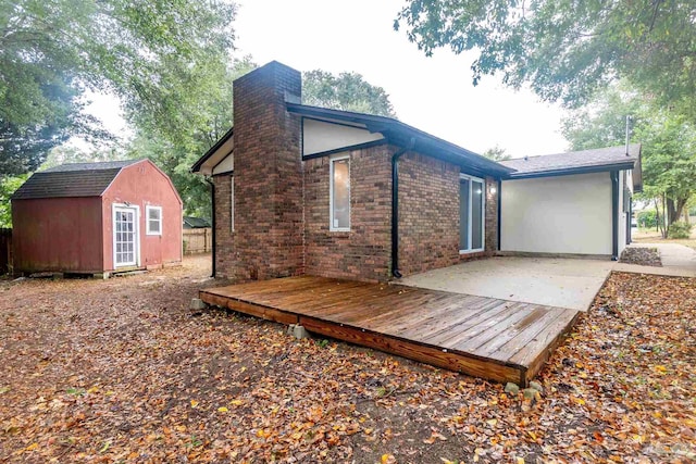 rear view of house with a storage shed and a wooden deck