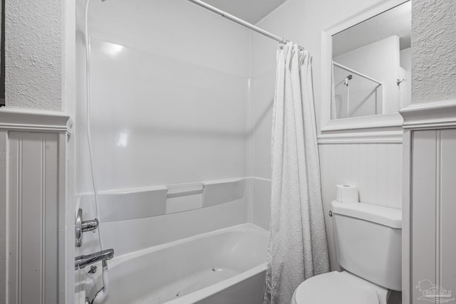 bathroom with shower / tub combo, wainscoting, and toilet