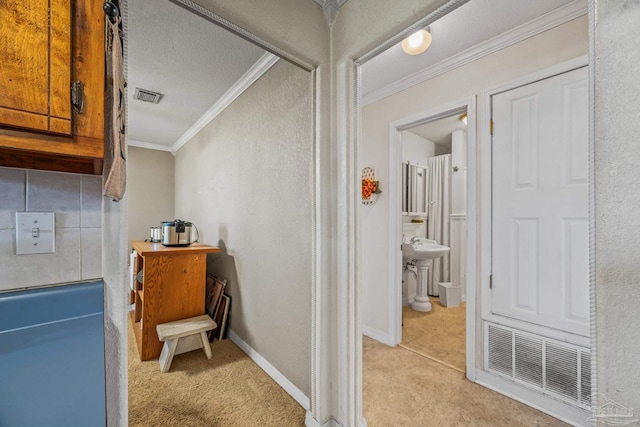 hall featuring baseboards, visible vents, and ornamental molding