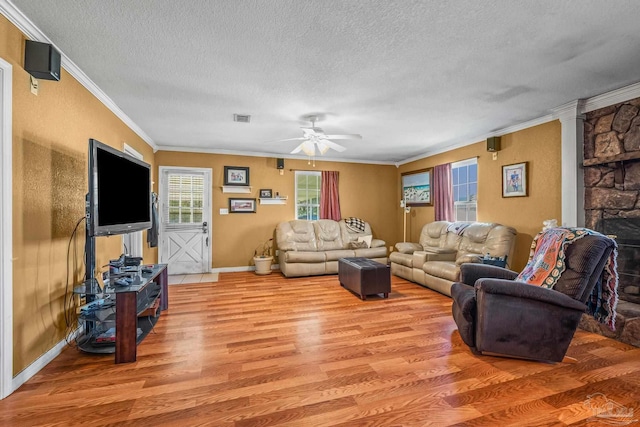 living area with visible vents, light wood-style flooring, ornamental molding, ceiling fan, and a textured ceiling