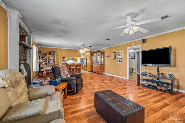 living room with visible vents, crown molding, light wood-style flooring, and ceiling fan